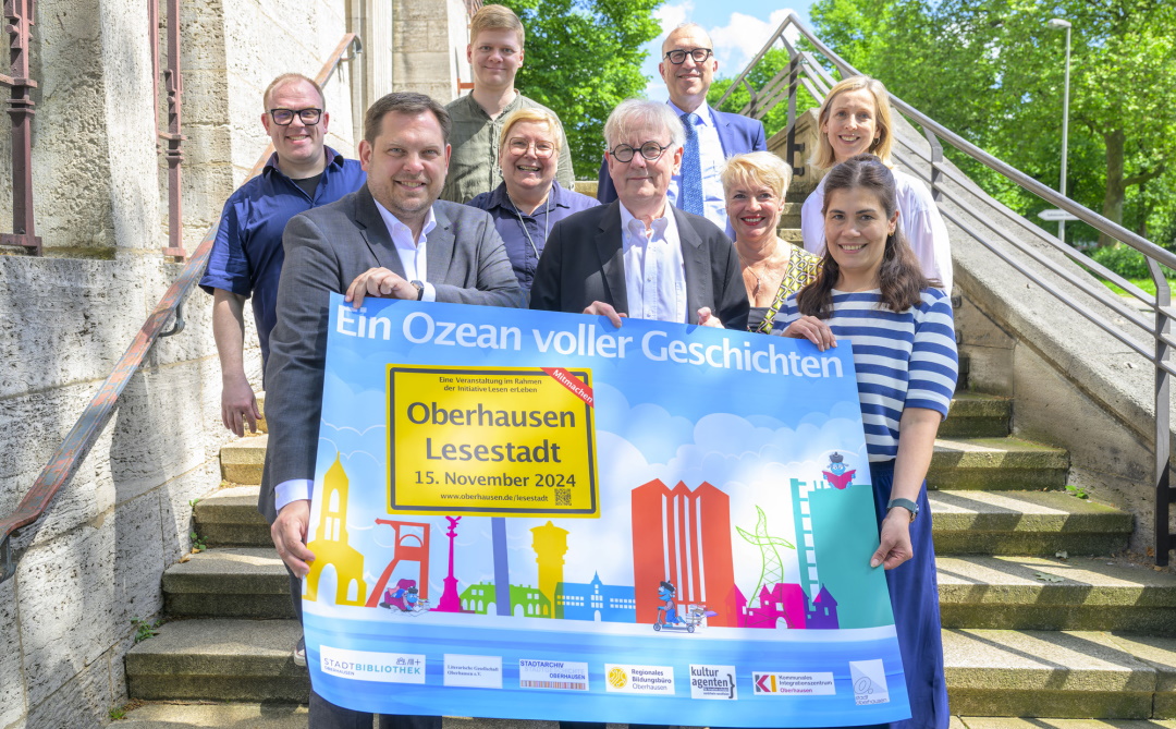 Oberbürgermeister Daniel Schranz (vorne links) wirbt gemeinsam mit Kulturdezernent Apostolos Tsalastras, Stadtbibliotheksleiterin Diana Bengel, Wilhelm Kurze (Literarische Gesellschaft), Kulturagent Jens Niemeier, Kirsten Linden-Gaflig (Schulbibliothekarische Arbeitsstelle), Petra Salewsky (Kommunales Integrationszentrum), Anna Derichs (Bert-Brecht-Bildungszentrum) und Daniel Simon Böhmer (Stadtarchiv) für die Aktion Oberhausen Lesestadt 2024