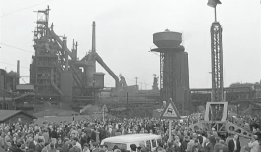 Szenefoto vom WDR-Dokumentarfilm, das den großen Menschenauflauf während der Dreharbeiten vor der eindrucksvollen Industriekulisse der Hüttenwerke Oberhausen zeigt. (rechtefreies Standbild)