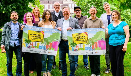 Oberbürgermeister Berg und Miarbeitende zeigen das Plakat zur Lesestadt 2026