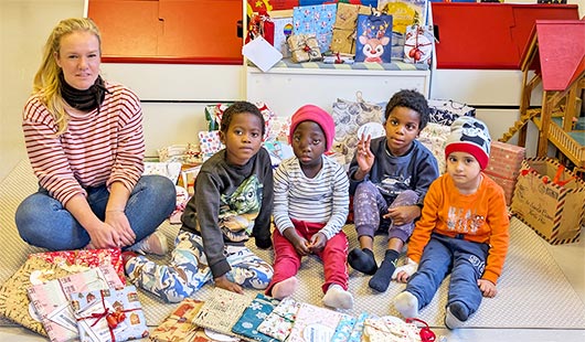 Anne Bender, Leiterin Kinderbibliothek, sowie vier Kindern des Friedensdorfs mit den Geschenken im Lernzimmer des Friedensdorfes. Foto: Stadt Oberhausen