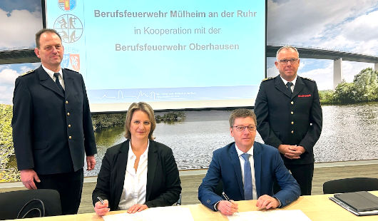 Mülheims Beigeordnete Anja Franke und Oberhausens Beigeordneter Michael Jehn unterzeichnen den Kooperationsvertrag. Hinter ihnen stehen Mülheims Feuerwehrchef Sven Werner (li.) und Oberhausens Feuerwehrchef Jürgen Jendrian (re.). (Foto: Feuerwehr Mülheim)