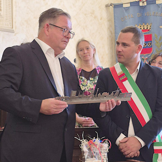 Bürgermeister Werner Nakot (li.) überreicht seinem Amtskollegen Mauro Usai eine stählerne Silhouette von Oberhausen. Foto: Stadt Oberhausen