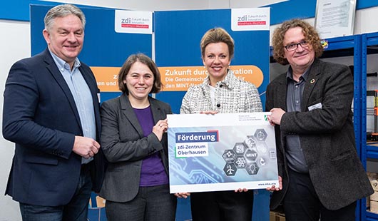 Der Beigeordnete Jürgen Schmidt, Insa Larson (zdi-Zentrum Oberhausen), Ministerin Ina Brandes und Professor Dr. Uwe Handmann (Professor für Neuroinformatik an der Hochschule Ruhr West, Leiter und Gründer des zdi-Zentrums Oberhausen) mit dem symbolischen Förderbescheid für das zdi-Zentrum Oberhausen Quelle: MKW NRW / Caroline Seidel