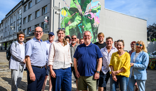 Apostolos Tsalastras, Kulturdezernent, Sabine Reimann, Künstlerin des Wandgemäldes und Ralf Bohnes, Bezirksbürgermeister stehen mit Beteiligten vor dem Wandbild (Foto: Stadt Oberhausen/Tom Thoene)