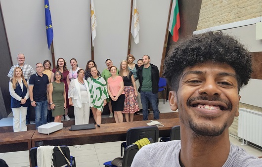 Gruppenbild als Selfie aufgenommen, der Fotograf lächelt im Vordergrund freundlich in die Kamera