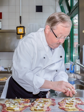 Foto zeigt Oberbürgermeister Klaus Wehling beim Befüllen von Rouladen. 