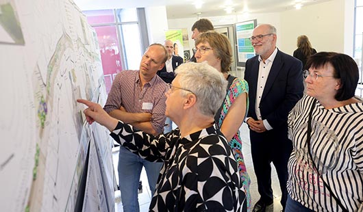 Martina Hoff von der Hoff & Koch Landschaftsarchitektur GmbH erläutert Robbie Schlagböhmer, Vorsitzender der STIG (hinten), Dr. Sven Wörmer vom Citymanagement (vorne links) sowie interessierten Bürgerinnen und Bürgern die Entwurfspläne. (Foto: RDN/Marco Stepniak)