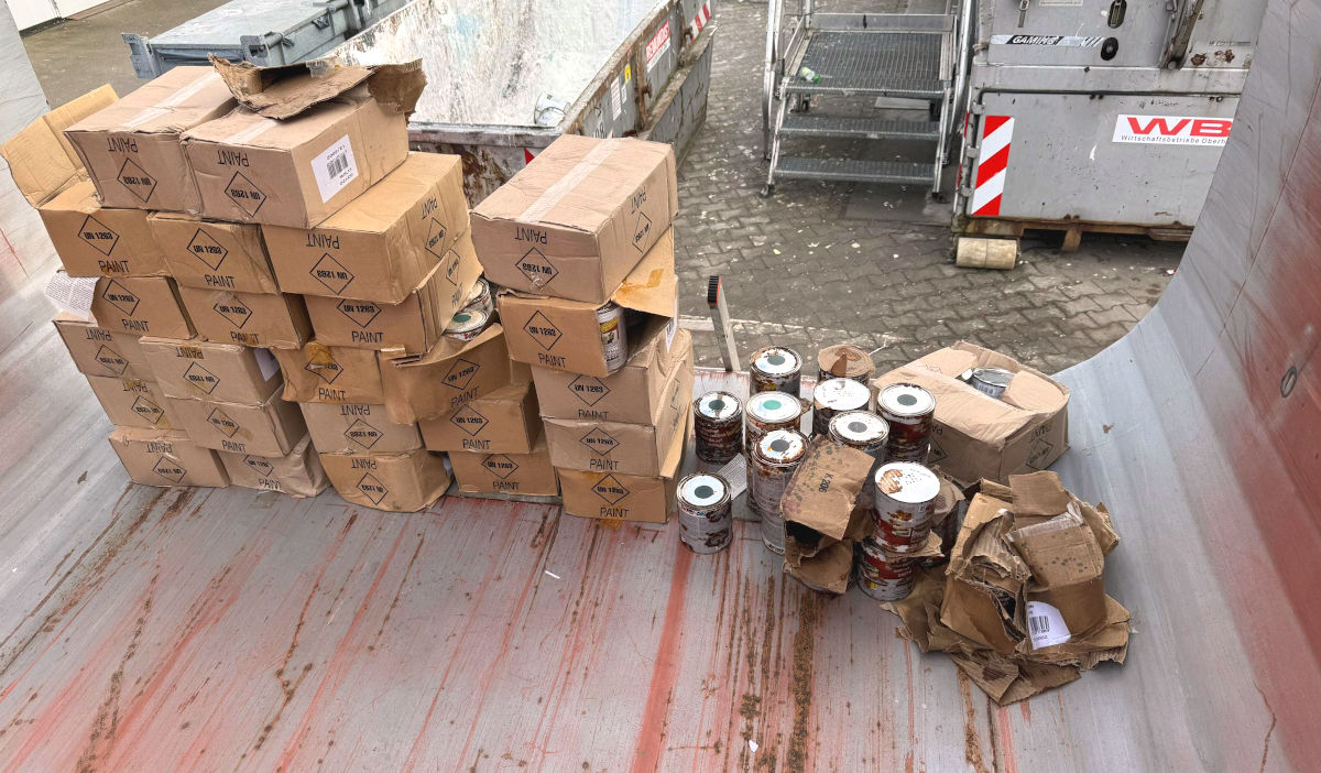 Kartons voller Lackdoesen auf einem Müllcontainer