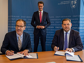Bild zeigt drei Personen bei Unterzeichnung der Planungsvereinbarung